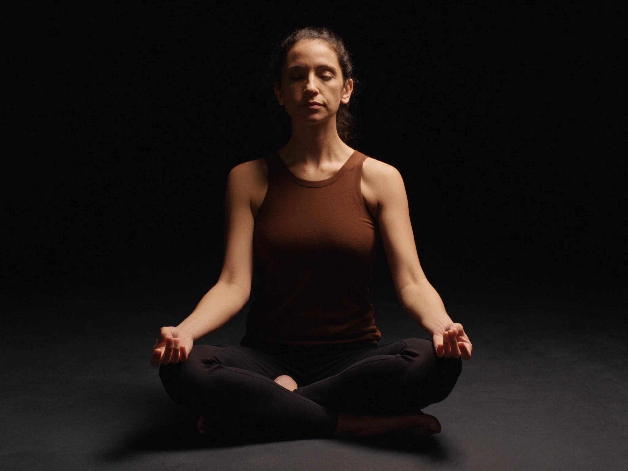 Person meditating seated by a window in soft light