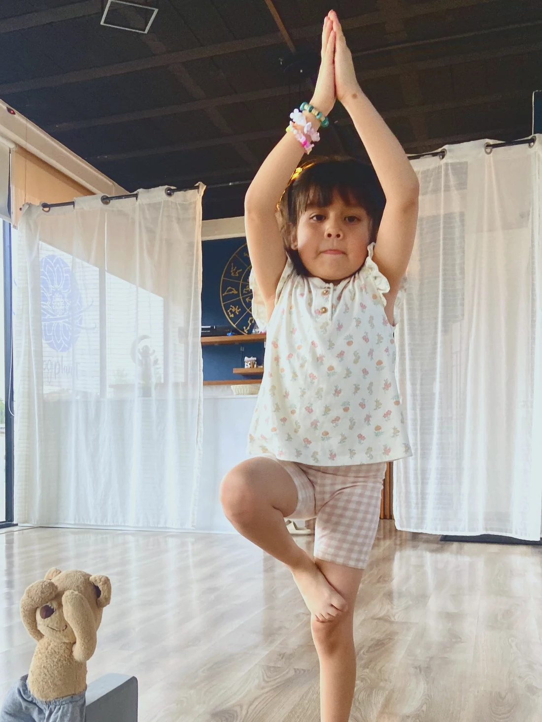 A girl in a yoga class at the studio, meditating with her teddy bear