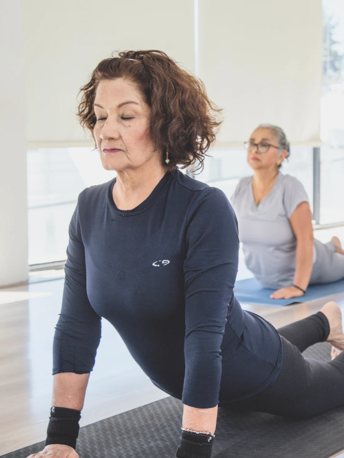 An older student in a gentle yoga class, guided by the instructor